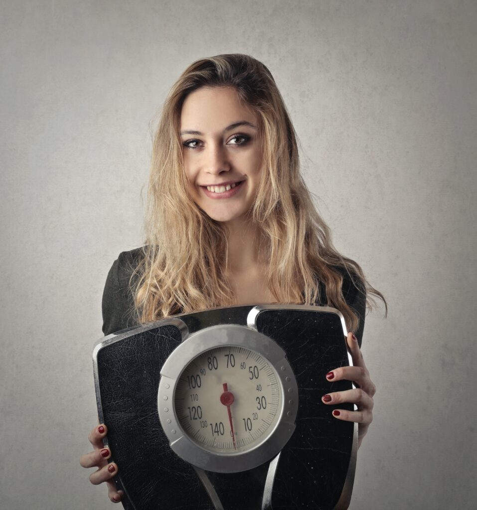 Woman smiling while standing on a weighing scale